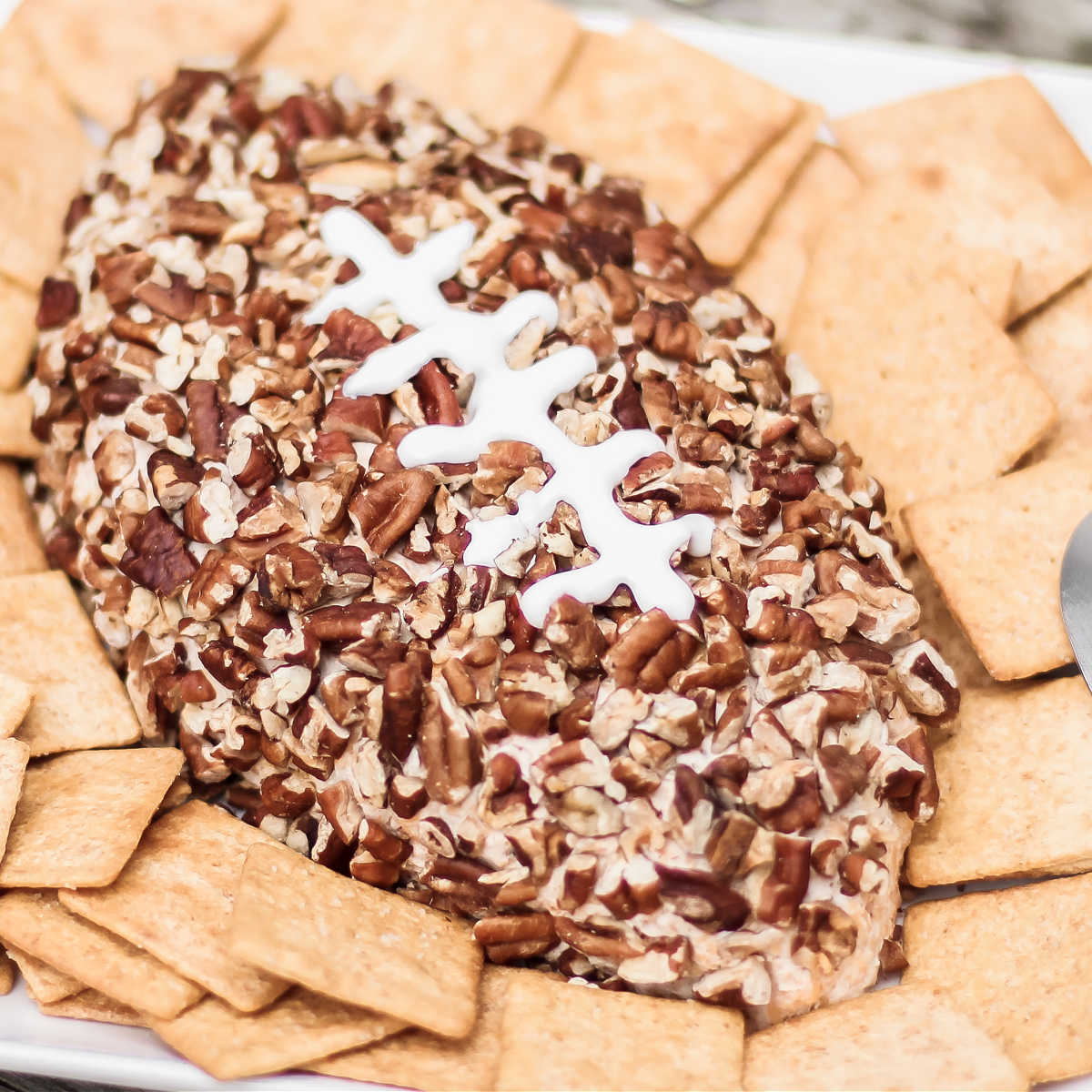 football shaped cheese ball covered in chopped pecans.