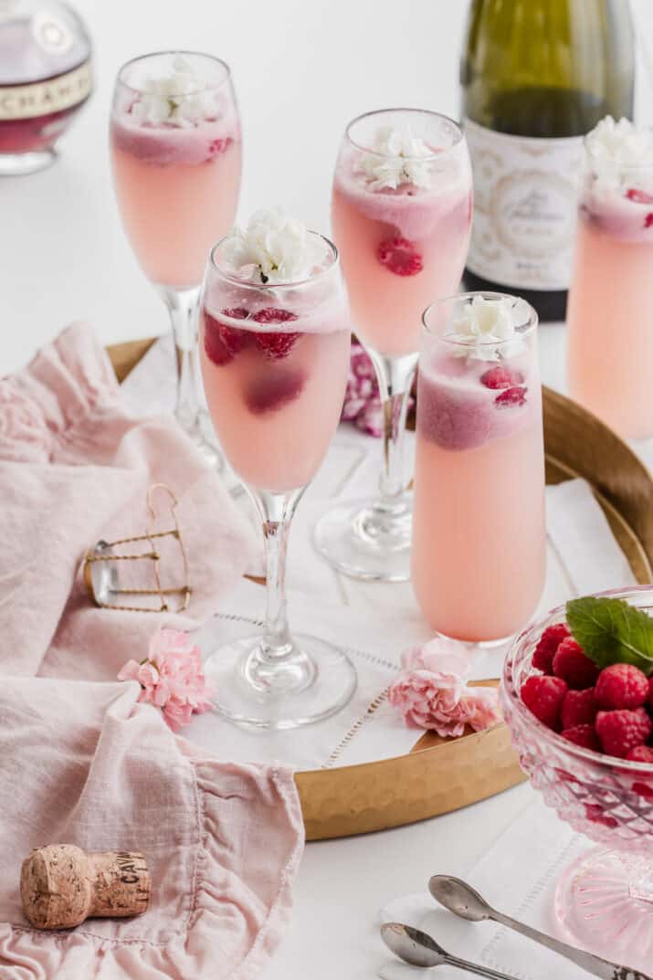 gold tray on white table, filled with champagne flutes and pink drinks.