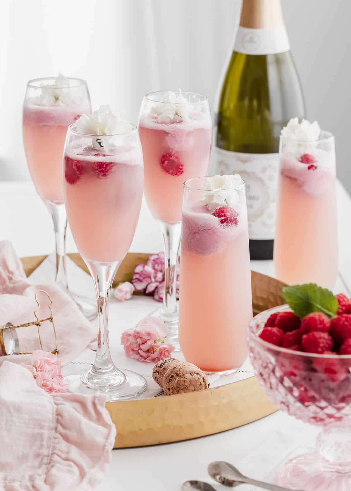 table with gold tray holding pink champagne drinks with fresh raspberries.