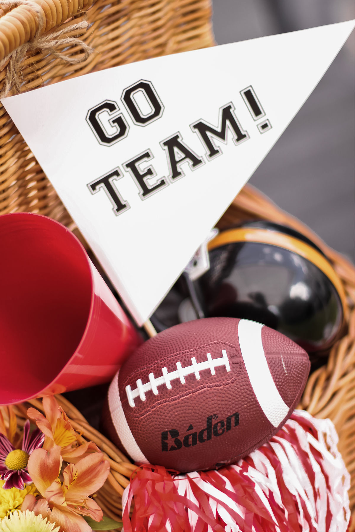 football decorations in a basket, includes pennant, football, pompom, and megaphone.