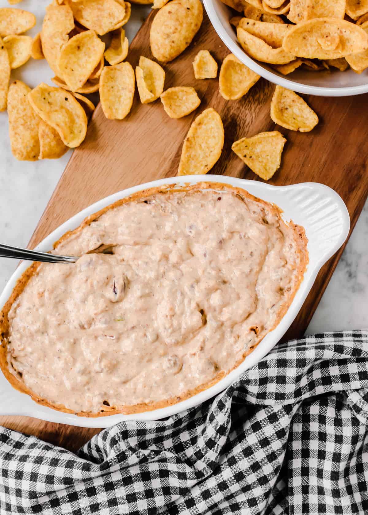 overhead view of creamy dip in white baking dish served with Fritos corn chip scoops.