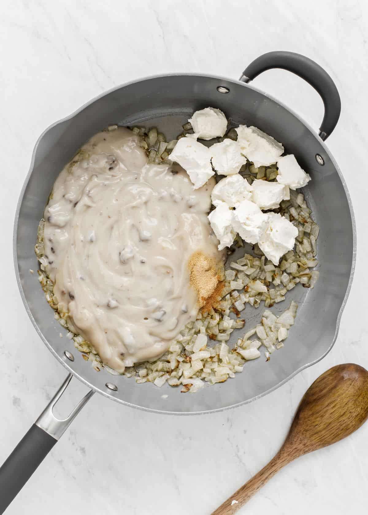 skillet with cooked onion and creamy soup and cream cheese inside.