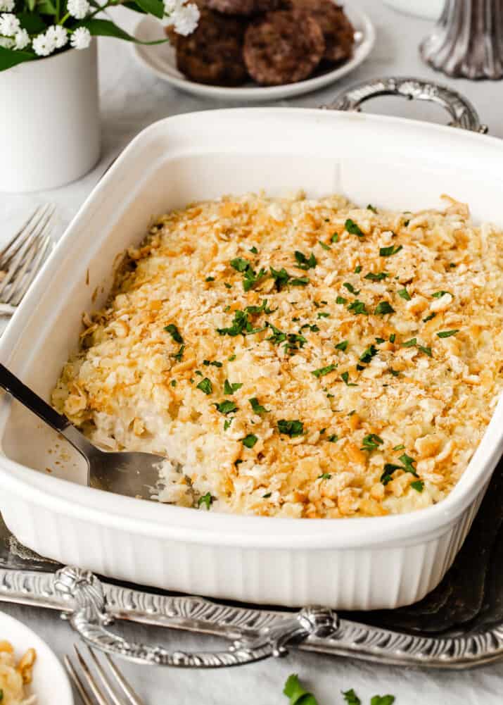 white baking dish of hash brown casserole sitting on silver tray on breakfast table.