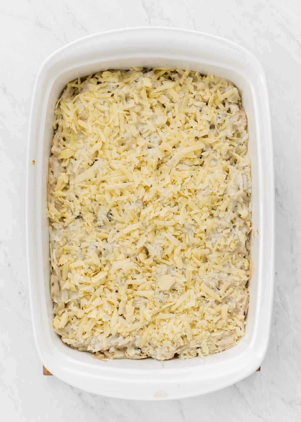 potato casserole with shredded cheese on top ready to bake.