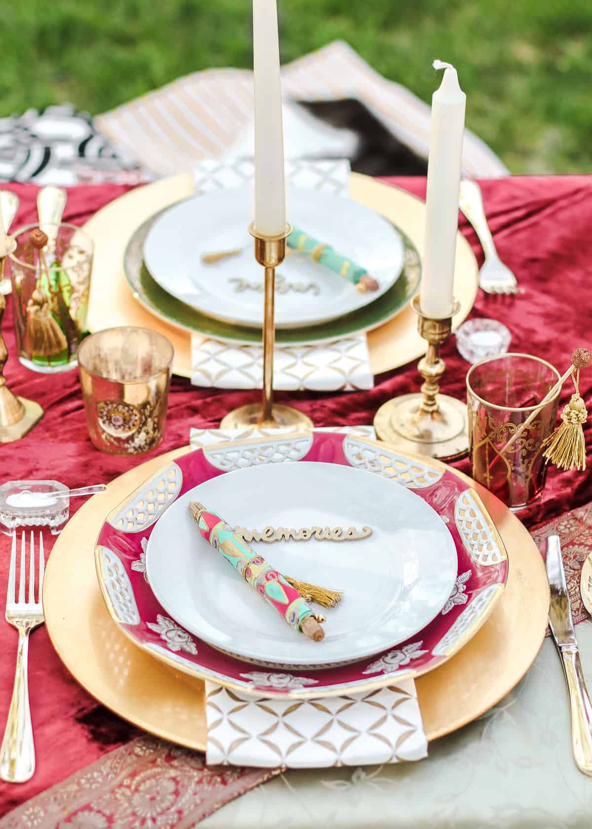 Table place setting with gold charger, decorative dinner plate, and white salad plate topped with colorful paper scroll.