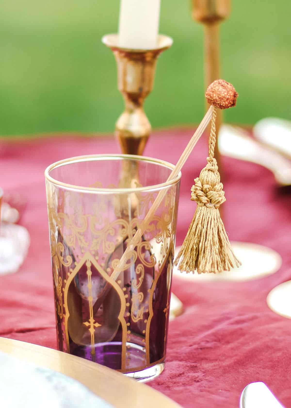 Moroccan tea glass with gold tassel stir stick inside.