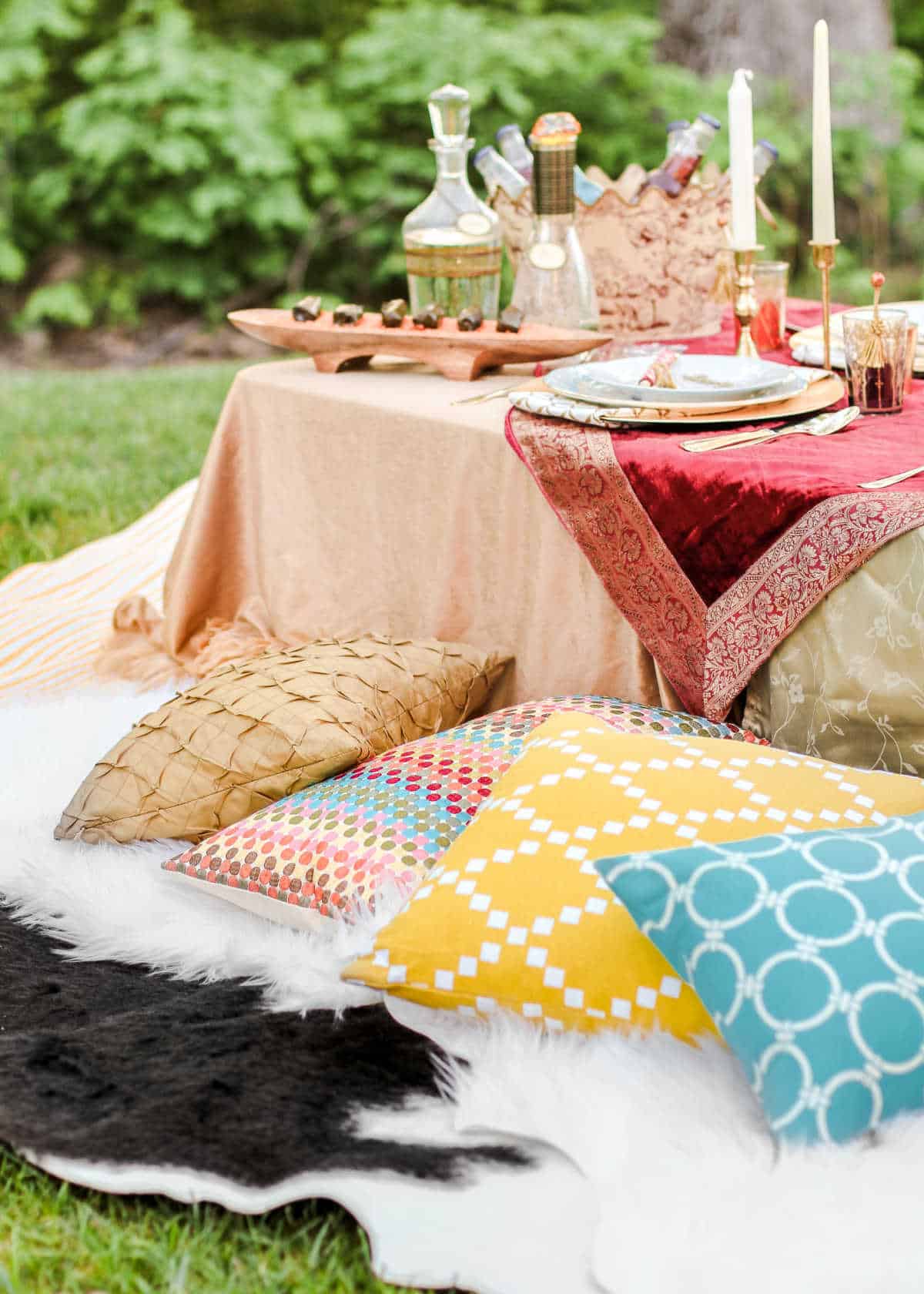 low party table outside with rugs and pillows to sit on.