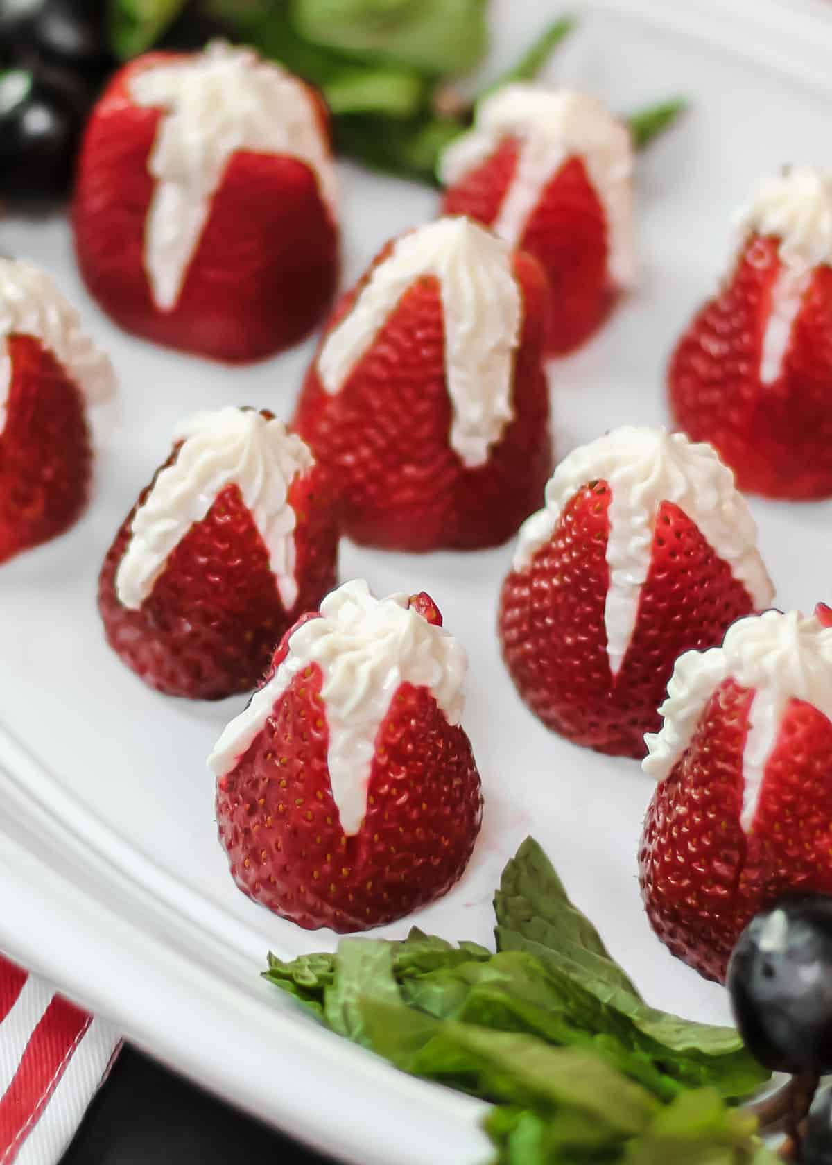 strawberries stuffed with cheesecake filling, on white platter.