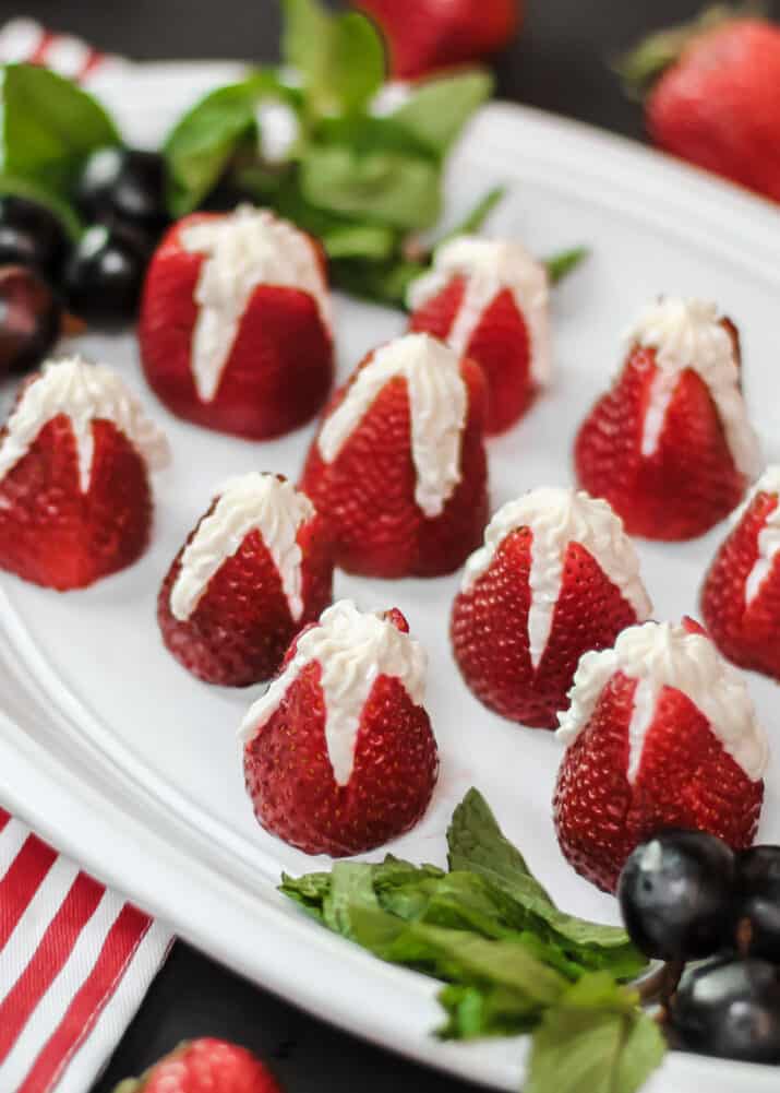 strawberries stuffed with cheesecake on white platter.