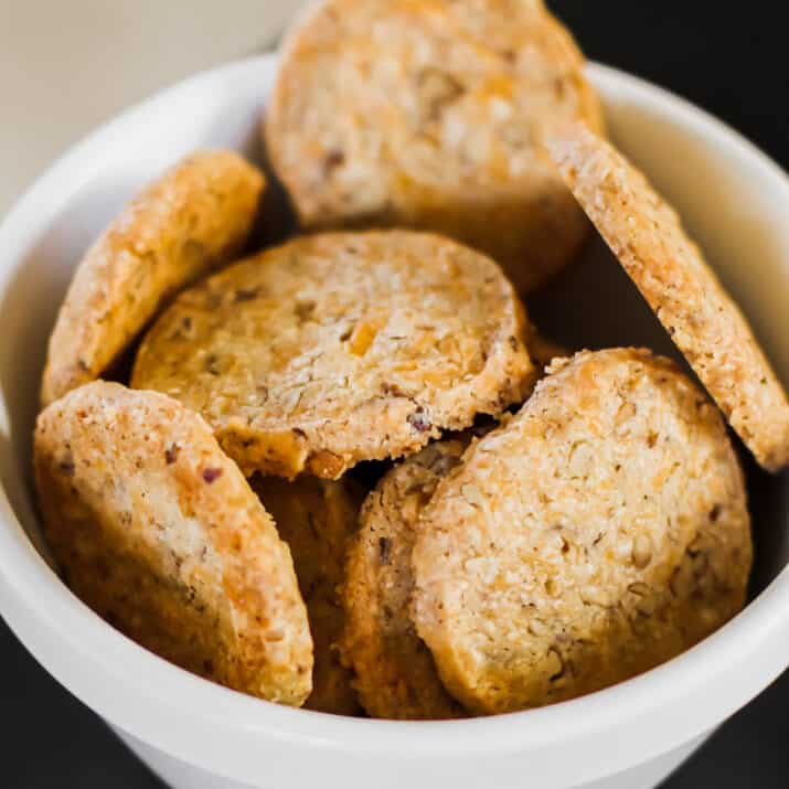 savory cheese coins crackers piled in small white bowl.