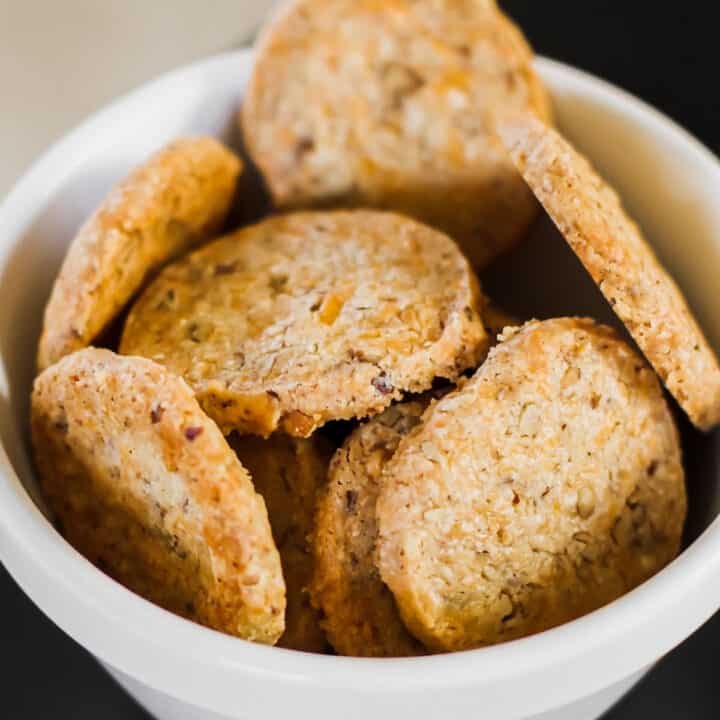 savory cheese coins crackers piled in small white bowl.