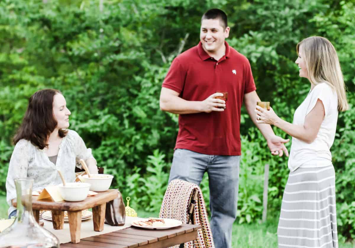man and two women socializing at a backyard party.