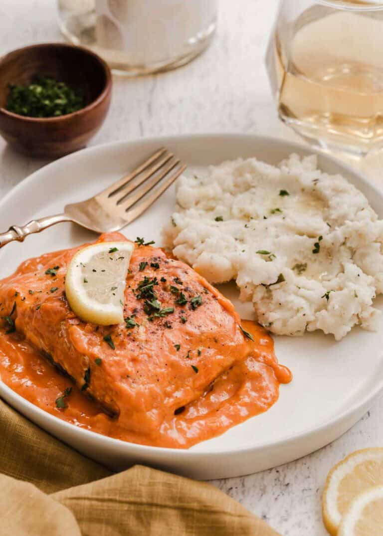 salmon fillet in red sauce on plate with mashed potatoes.