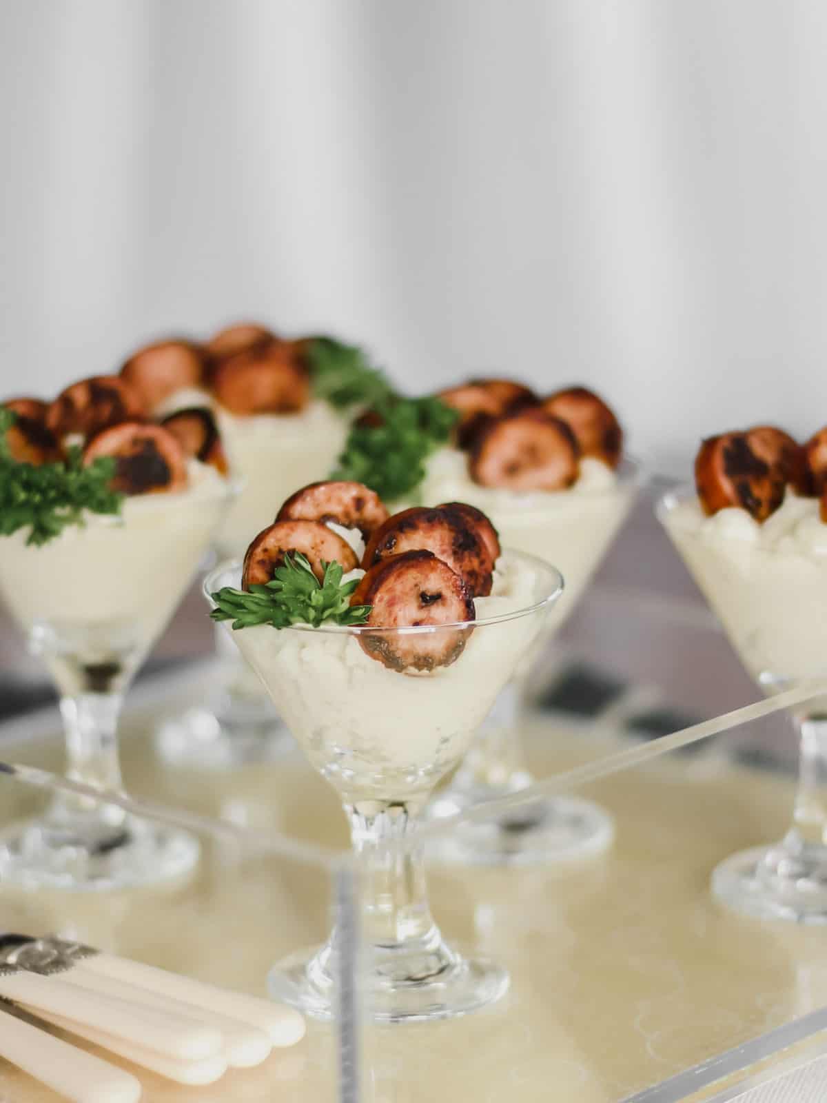 mini martini glasses filled with mashed potatoes and sausage medallions.