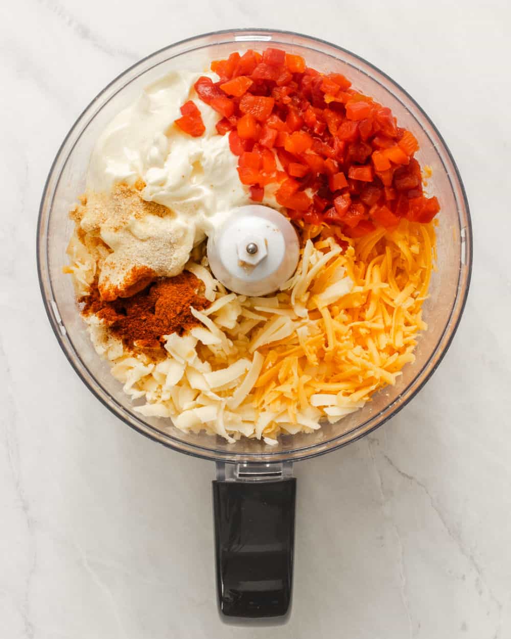 ingredients for pimento cheese inside a food processor. 