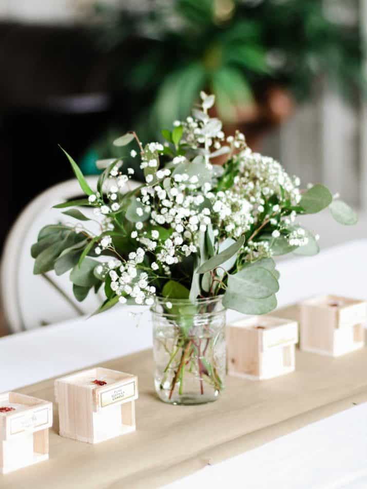 party table set up with greenery and babies breath, and small candles.