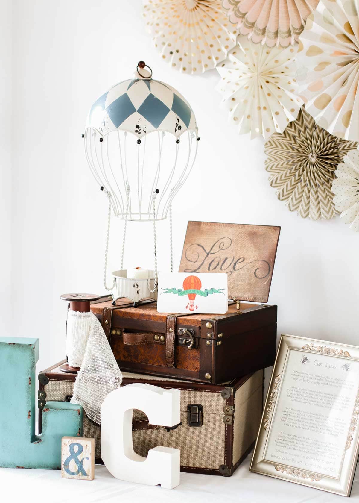 party decor for table with hanging air balloon, monogram letters, and vintage suitcases.