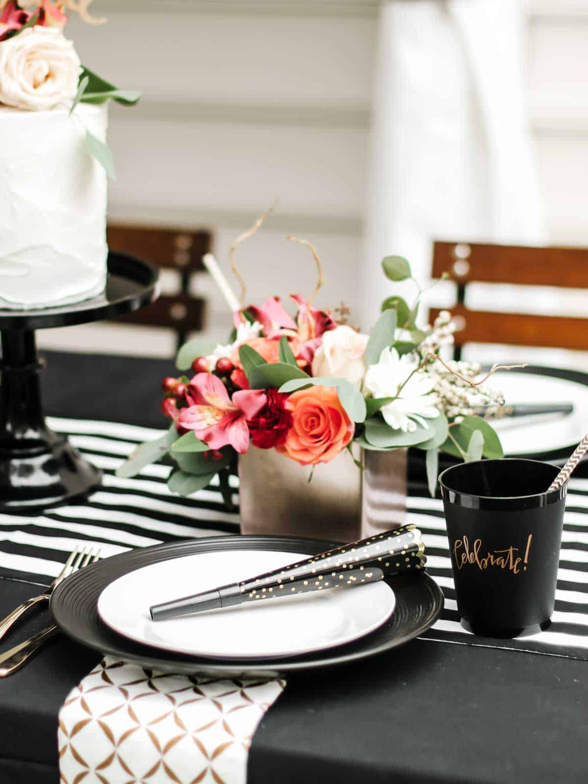 dinner table outside with black and white table decorations and colorful flower centerpiece. 