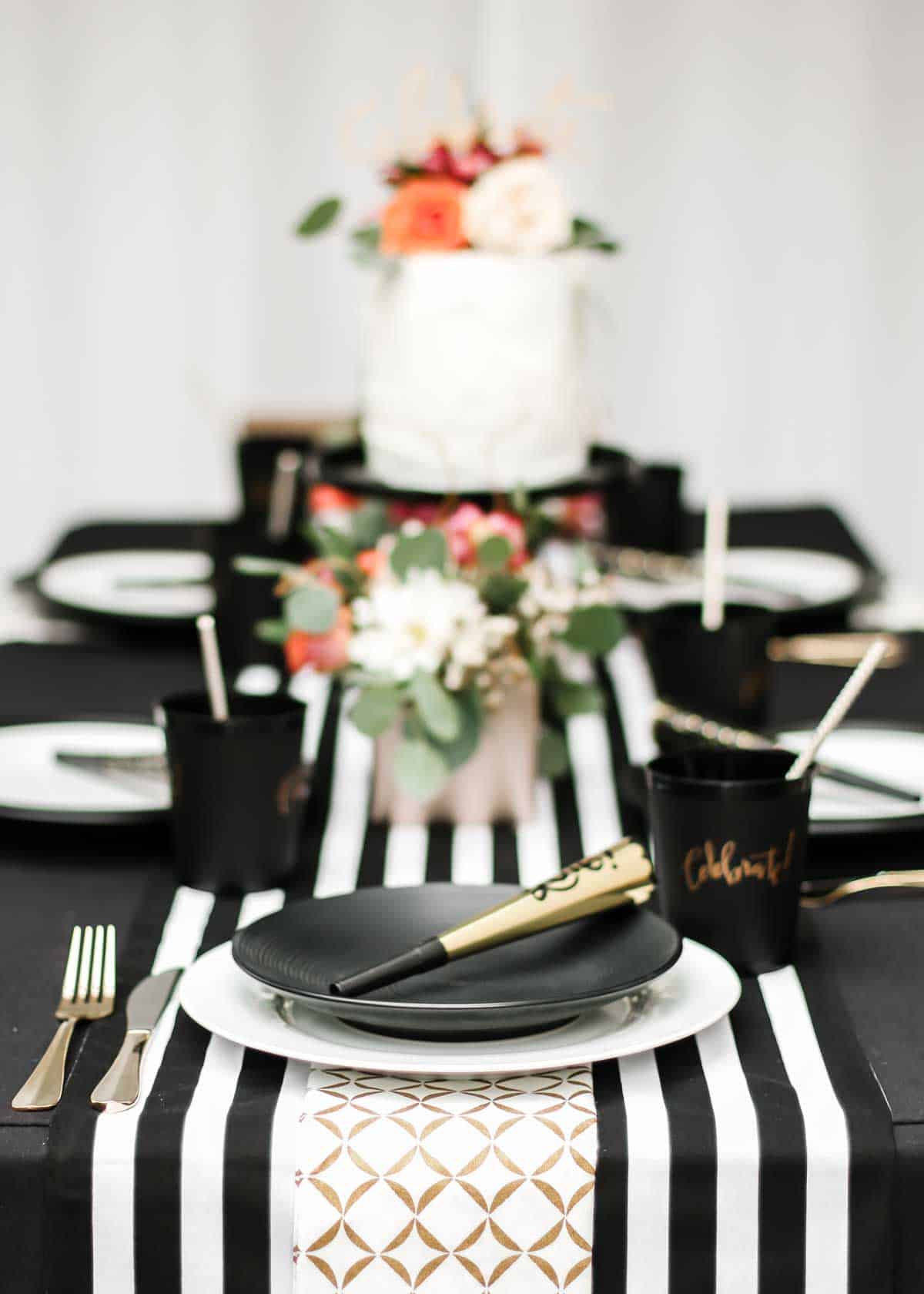 dinner table outside with black and white table decorations and colorful flower centerpiece.