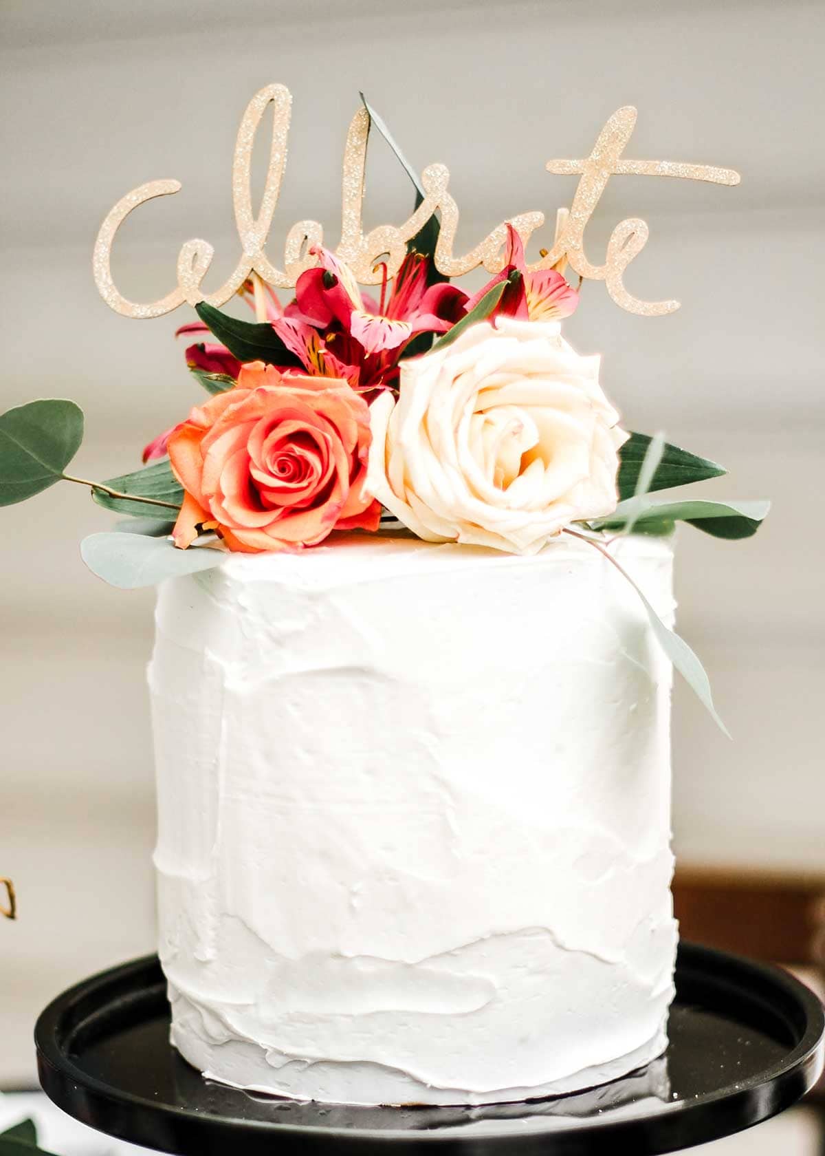 white cake with spring flowers on top with a Celebrate cake topper.
