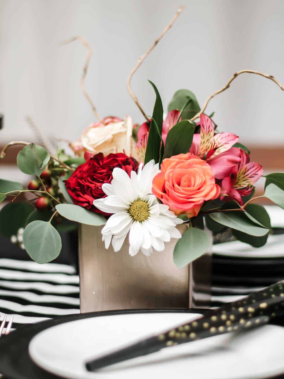 small pink and peach flower arrangement in square vase.