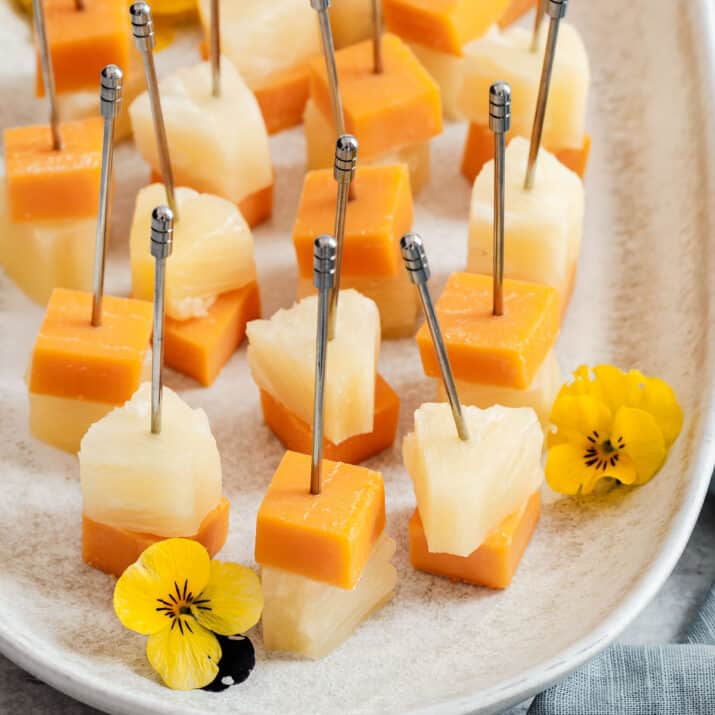 party picks with cheese cube and pineapple, on tray.