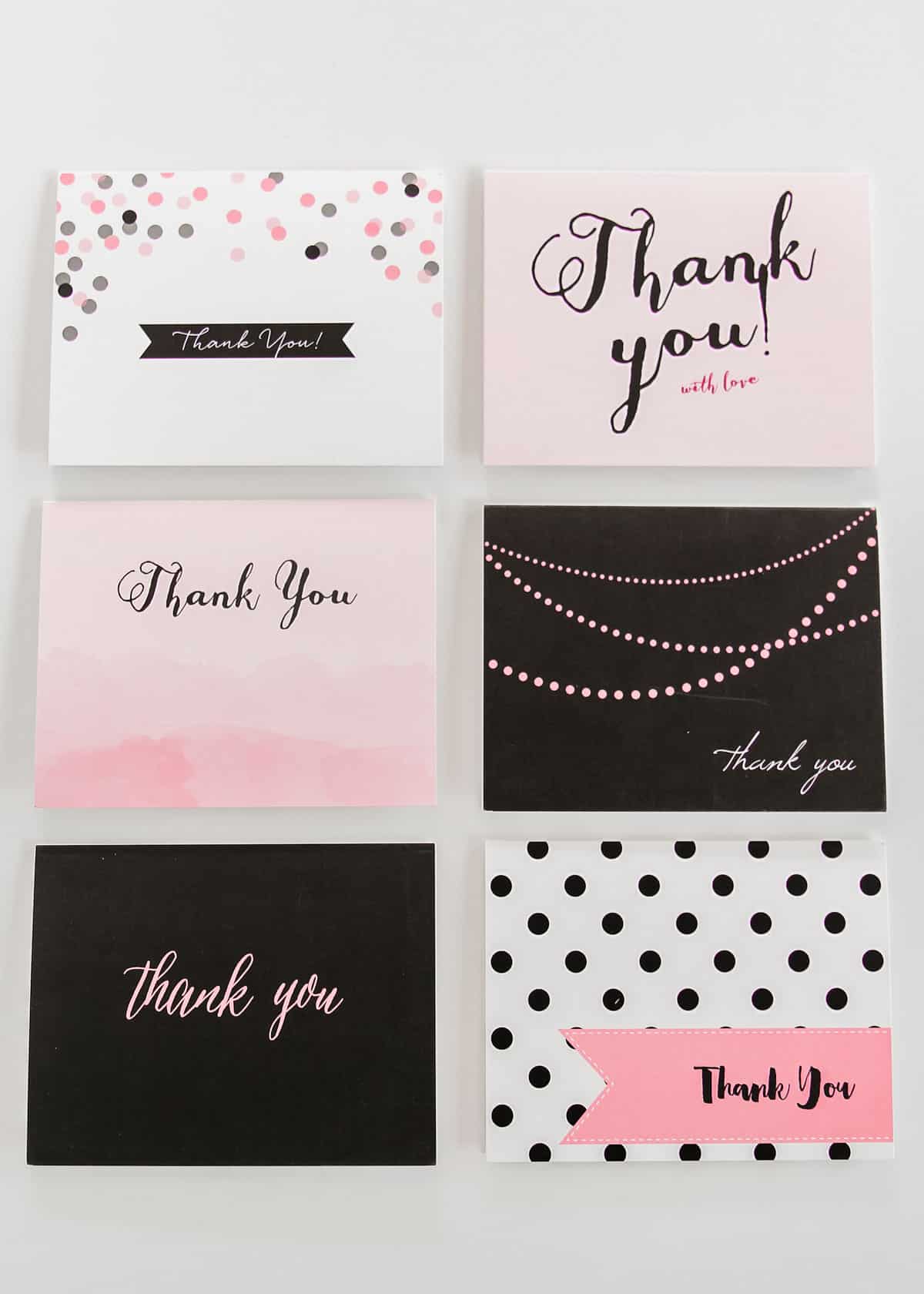 six different black and white and pink thank you cards, overhead view on white background.