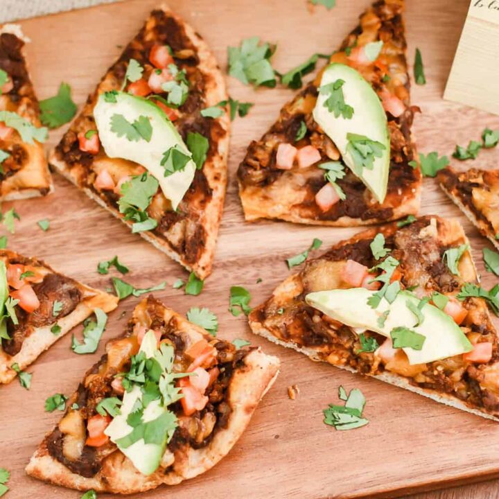 slices of chorizo flatbread pizza on wood board.