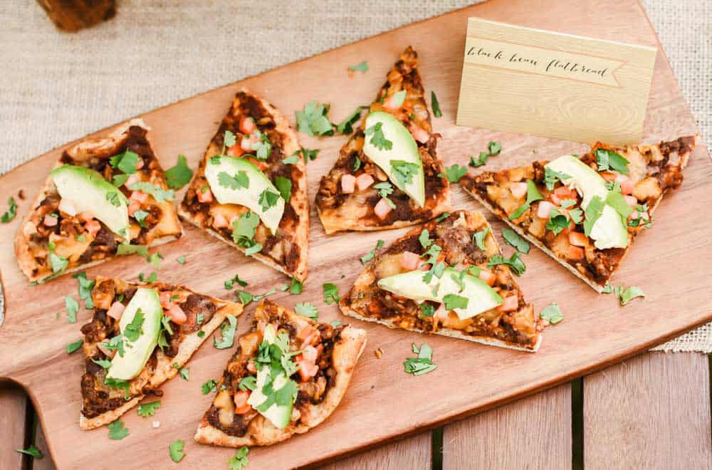 slices of black bean and chorizo flatbread pizza on wood board.