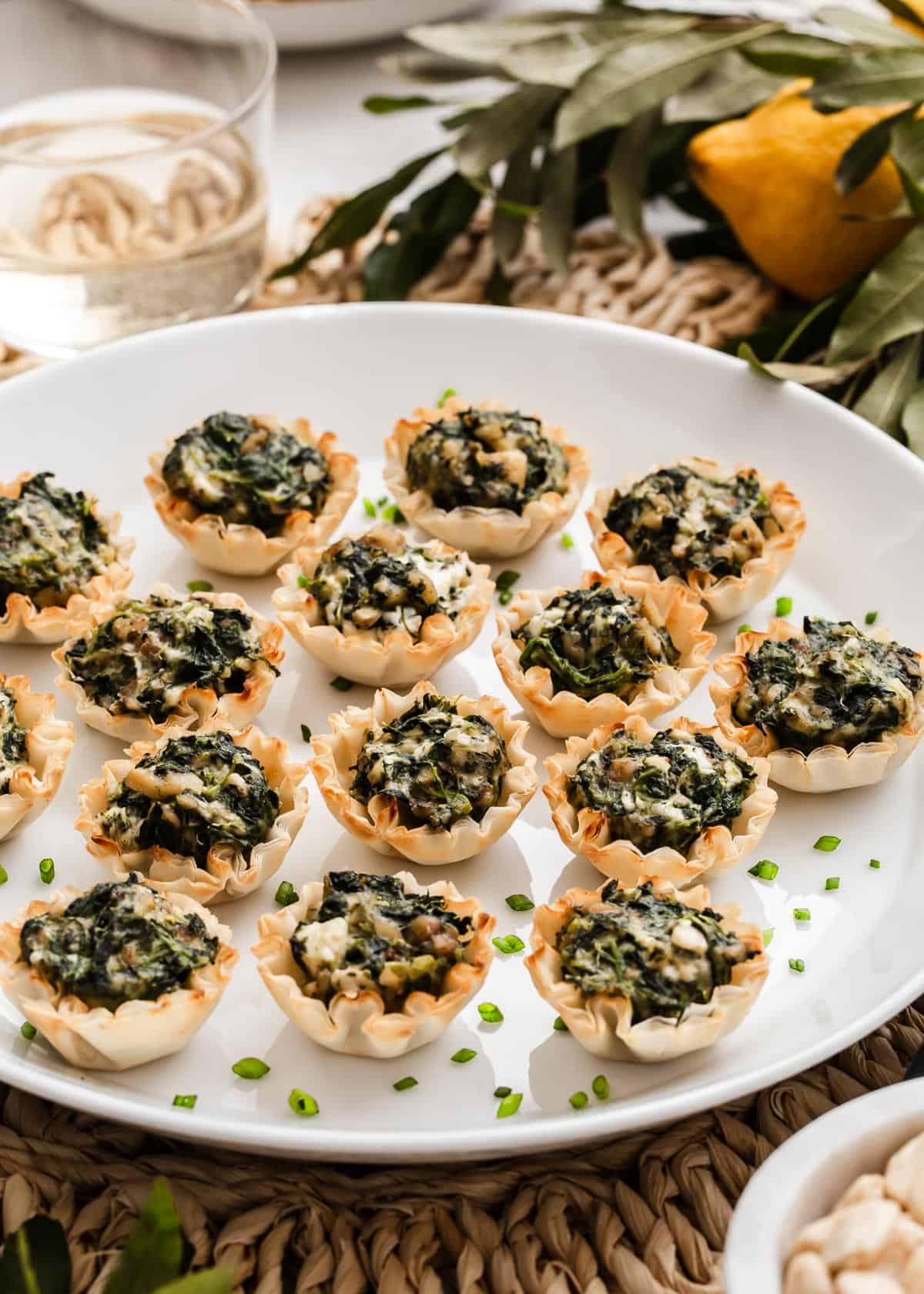 Mini phyllo shells filled with spinach spanakopita mix, served on white platter.
