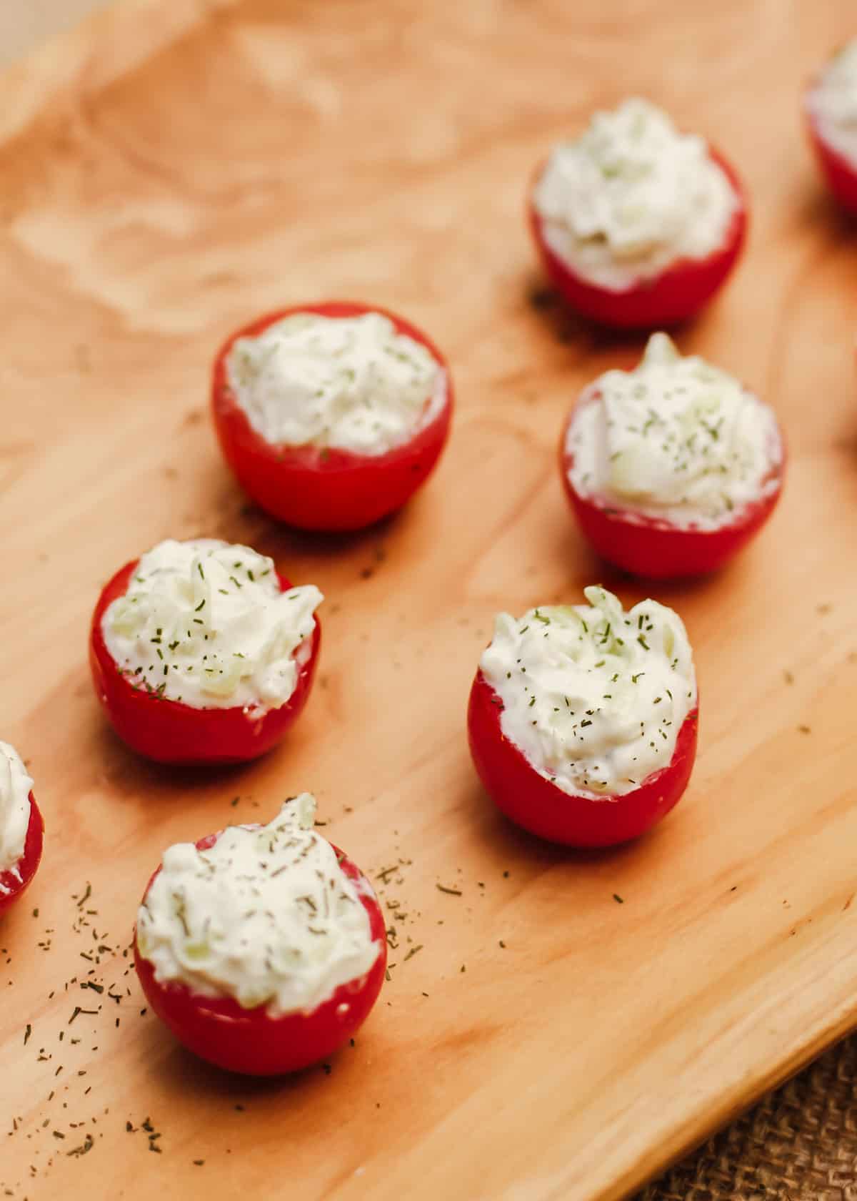 cherry tomatoes stuffed with cream filling, on wood dish.