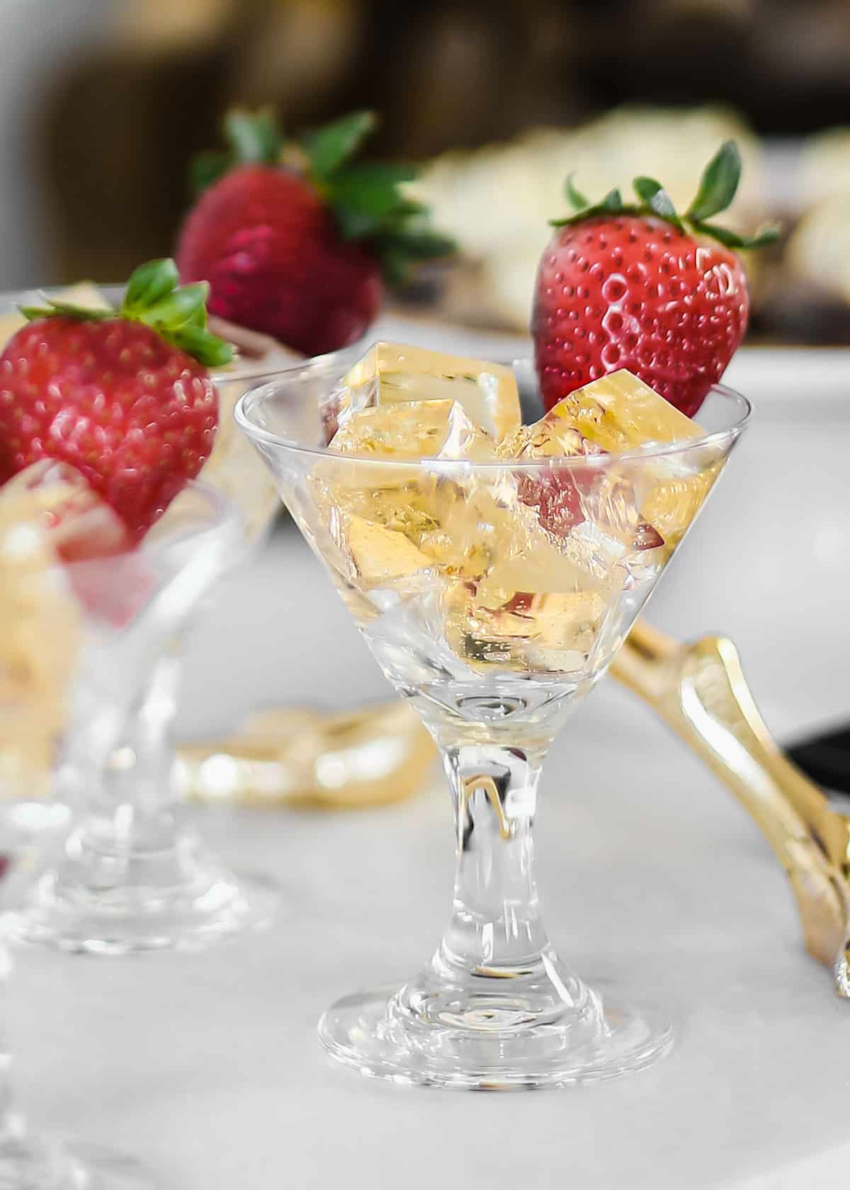 mini martini glasses filled with gold colored jello cut into tiny squares.