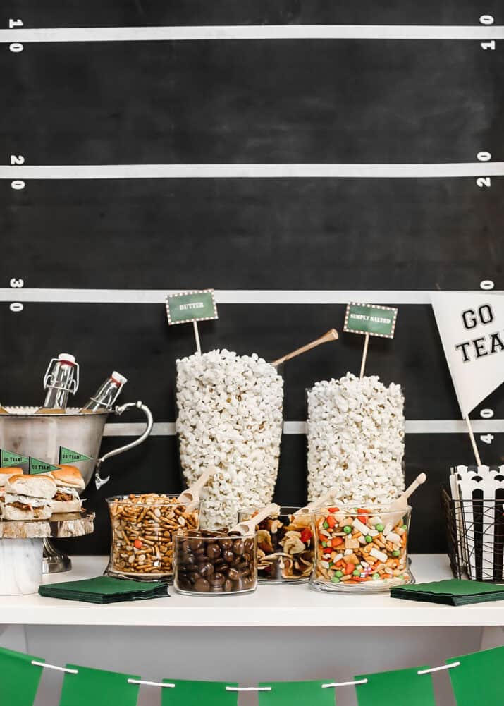 football themed popcorn bar with clear jars and bowls filled with toppings.
