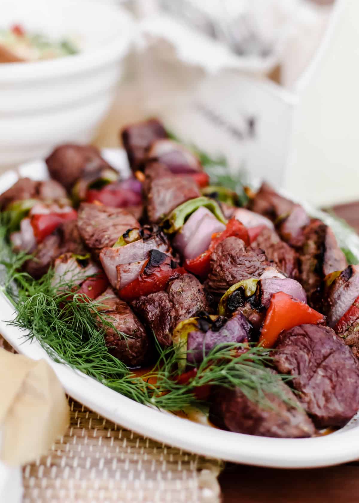 grilled beef kabobs on white platter.