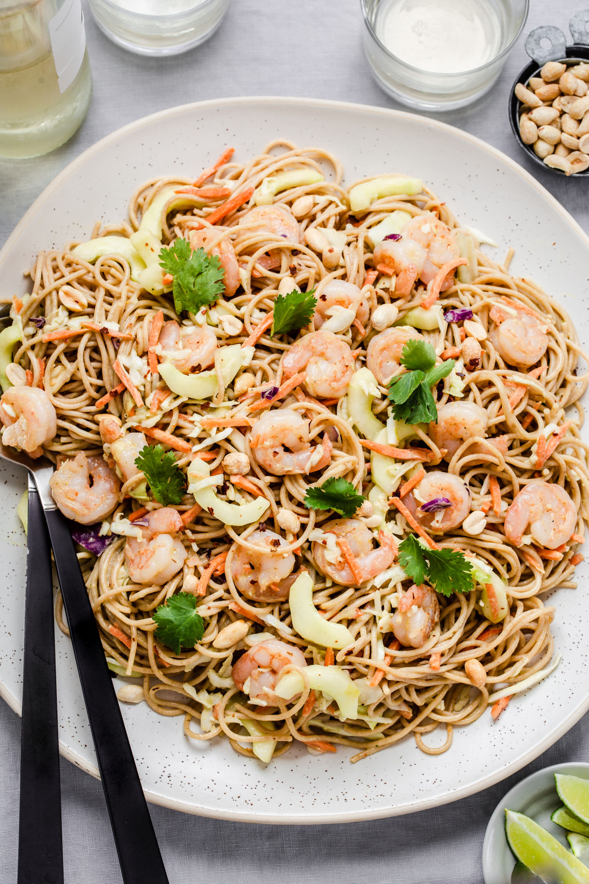 large platter of spaghetti noodle salad with shrimp, on blue table.