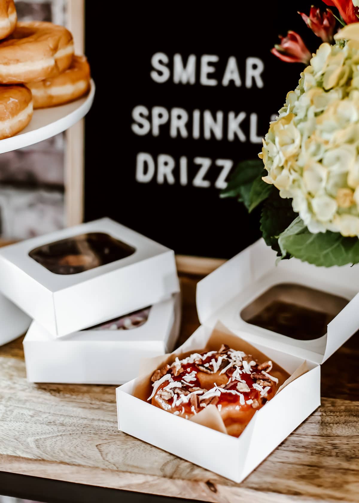 mini white bakery boxes with donuts inside.