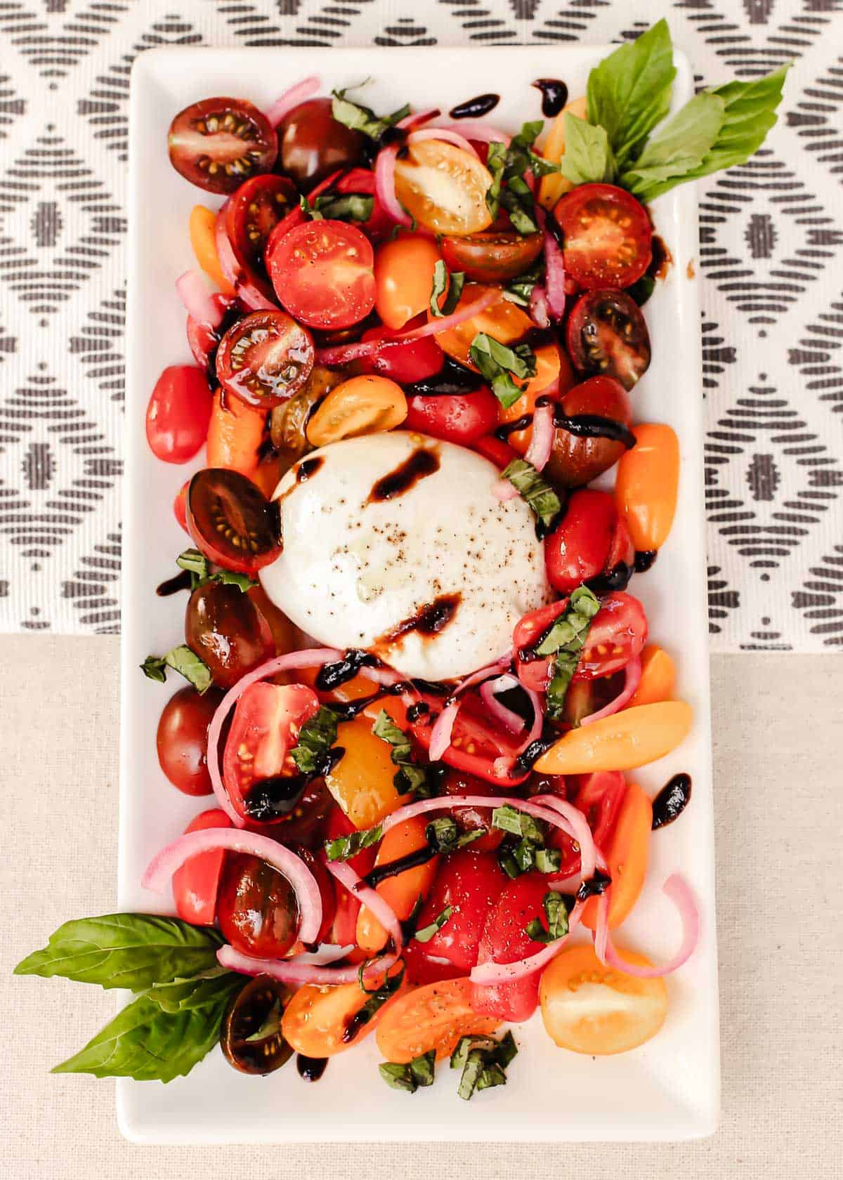 tomatoes and burrata salad on white platter.