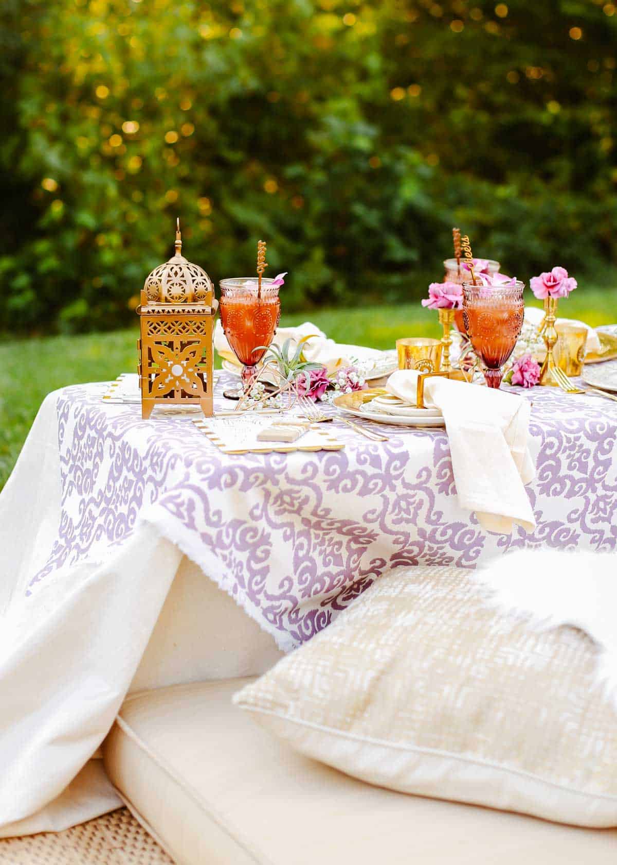 picnic style party table set up outside, with purple and gold tablescape.