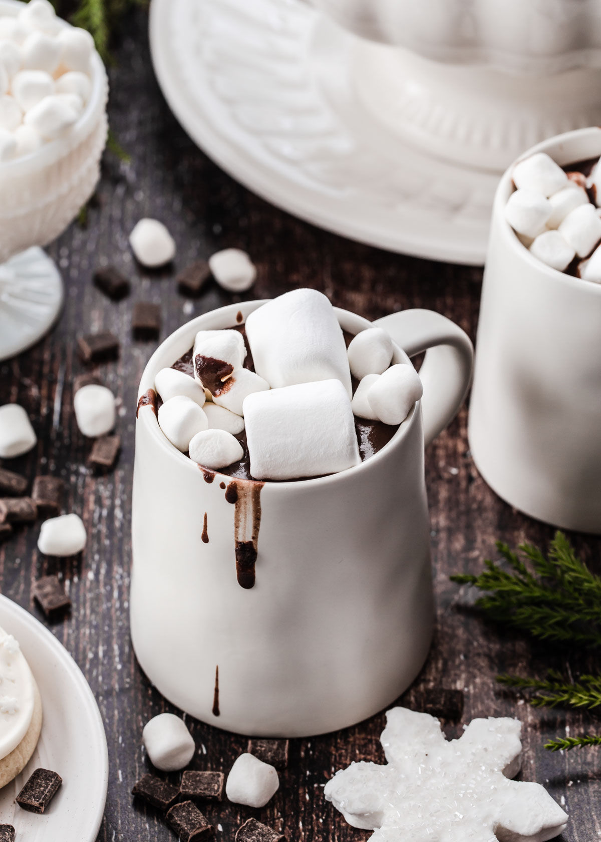 white mug filled with hot chocolate topped with big and small marshmallows, on wood table.