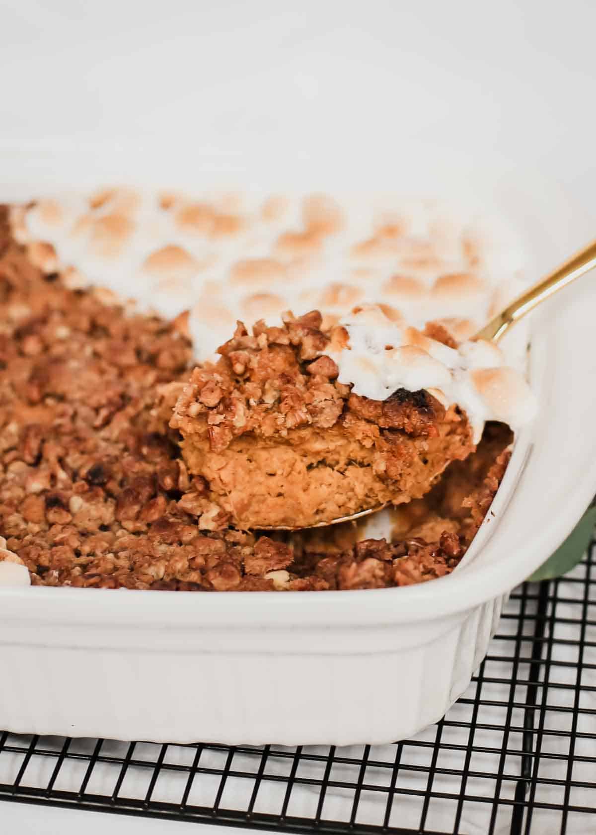 large spoon lifting out a scoop of sweet potato casserole.