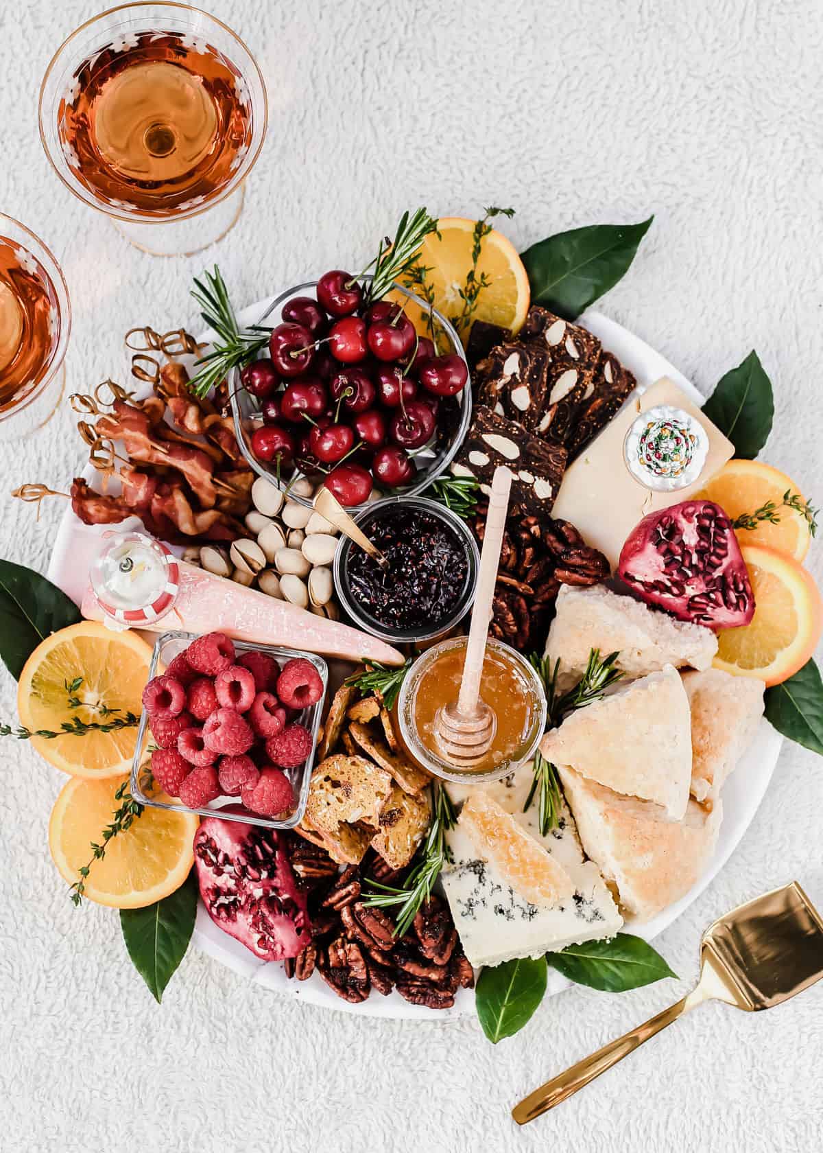 white table with round platter filled with brunch items like bacon, cheese, jam, nuts and fruit.