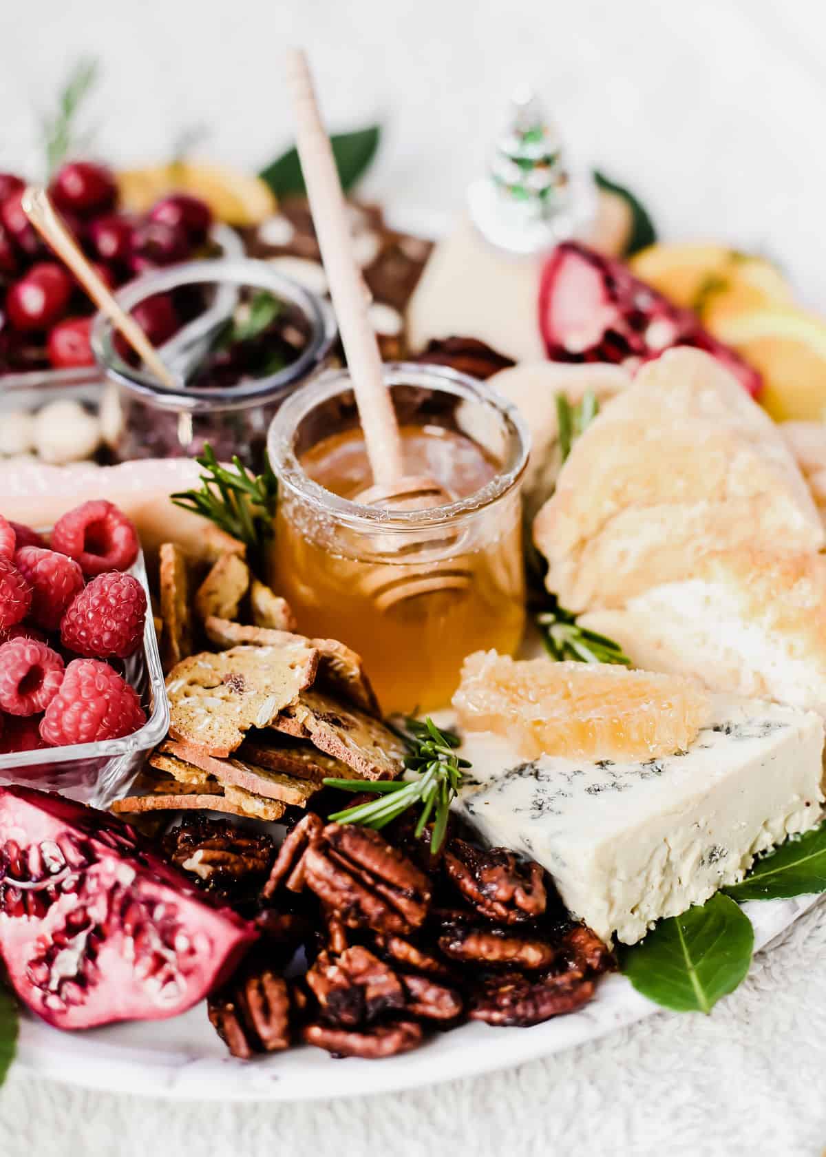 white platter filled with nuts, fruit and blue cheese with honey comb on top.