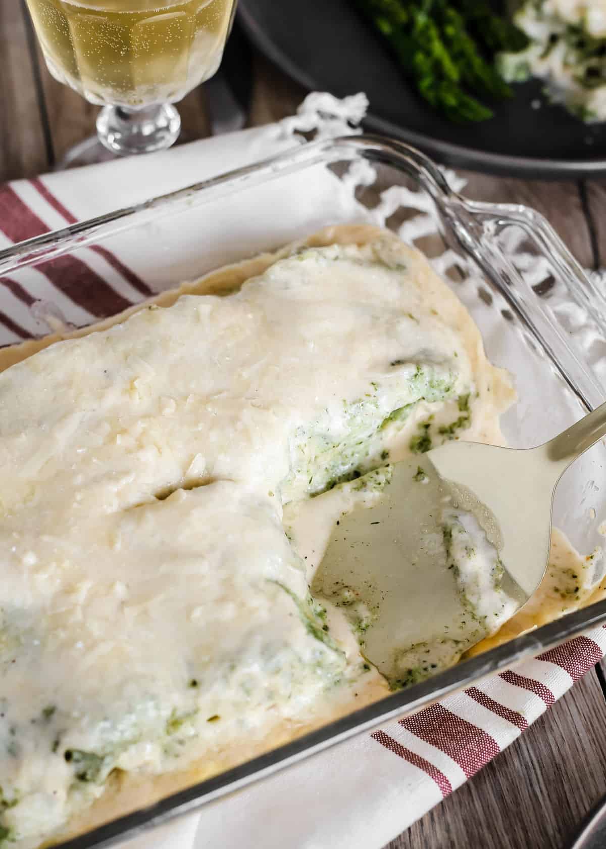 baking dish with cooked lasagna rolls covered in alfredo sauce.