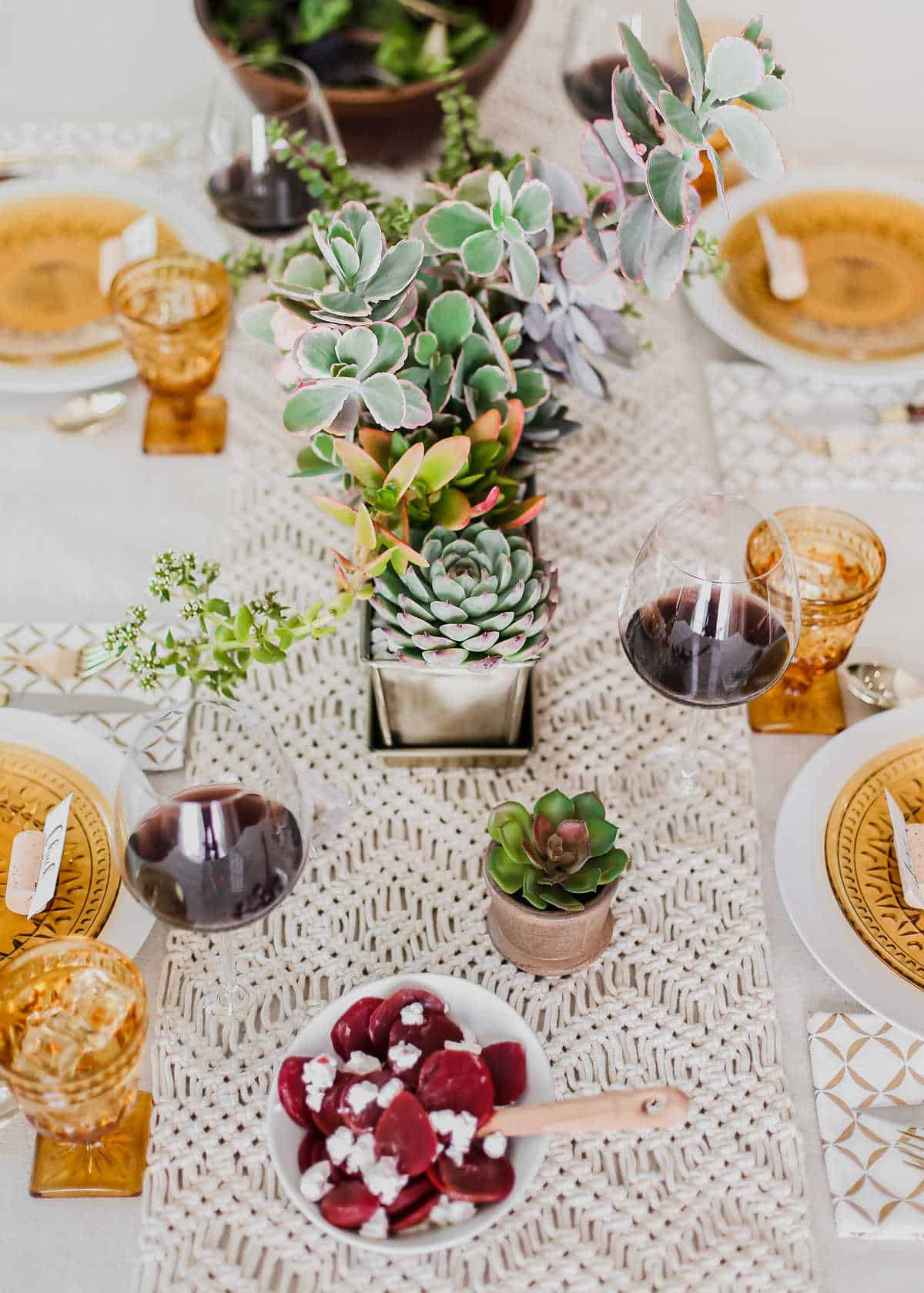 long tablescape with woven runner and amber glass plates and glasses and succulent centerpiece.