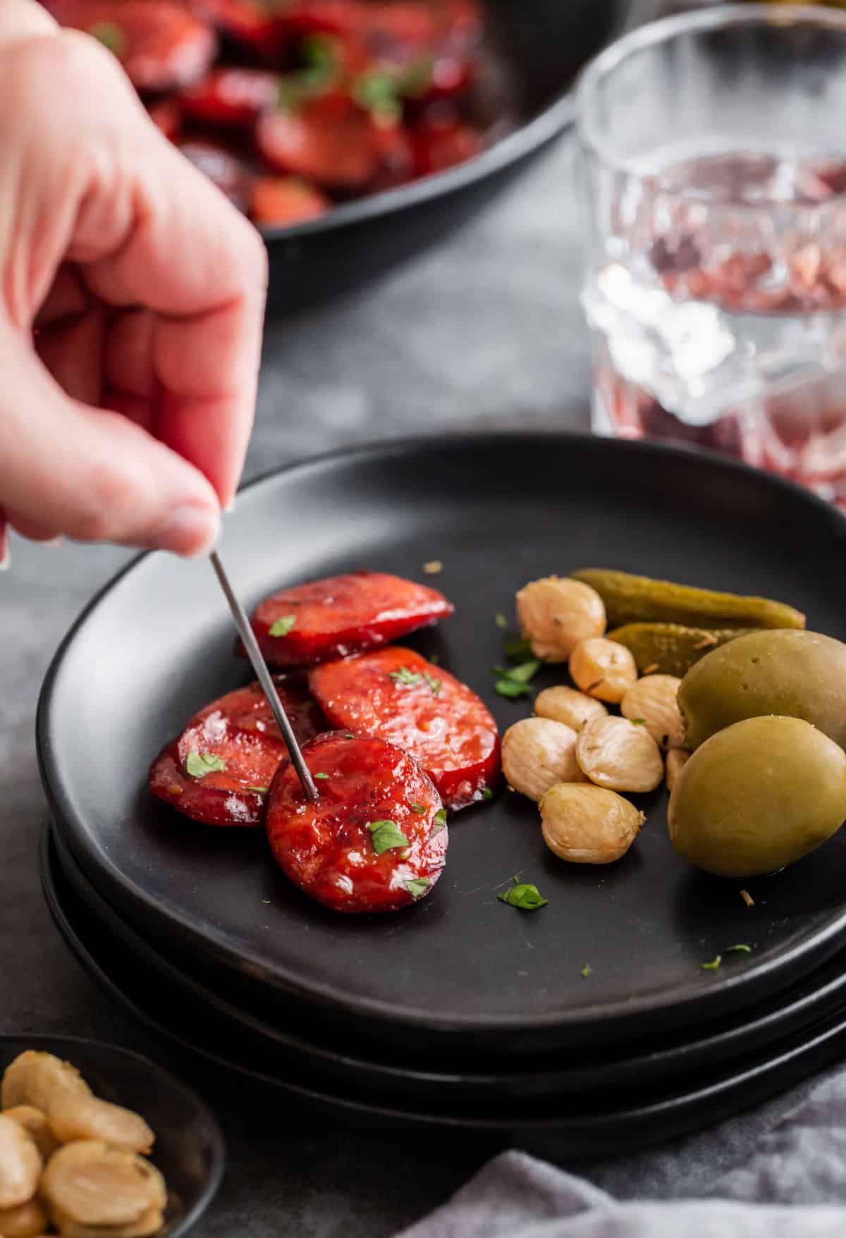 small black plate with appetizers and hand holding food pick.