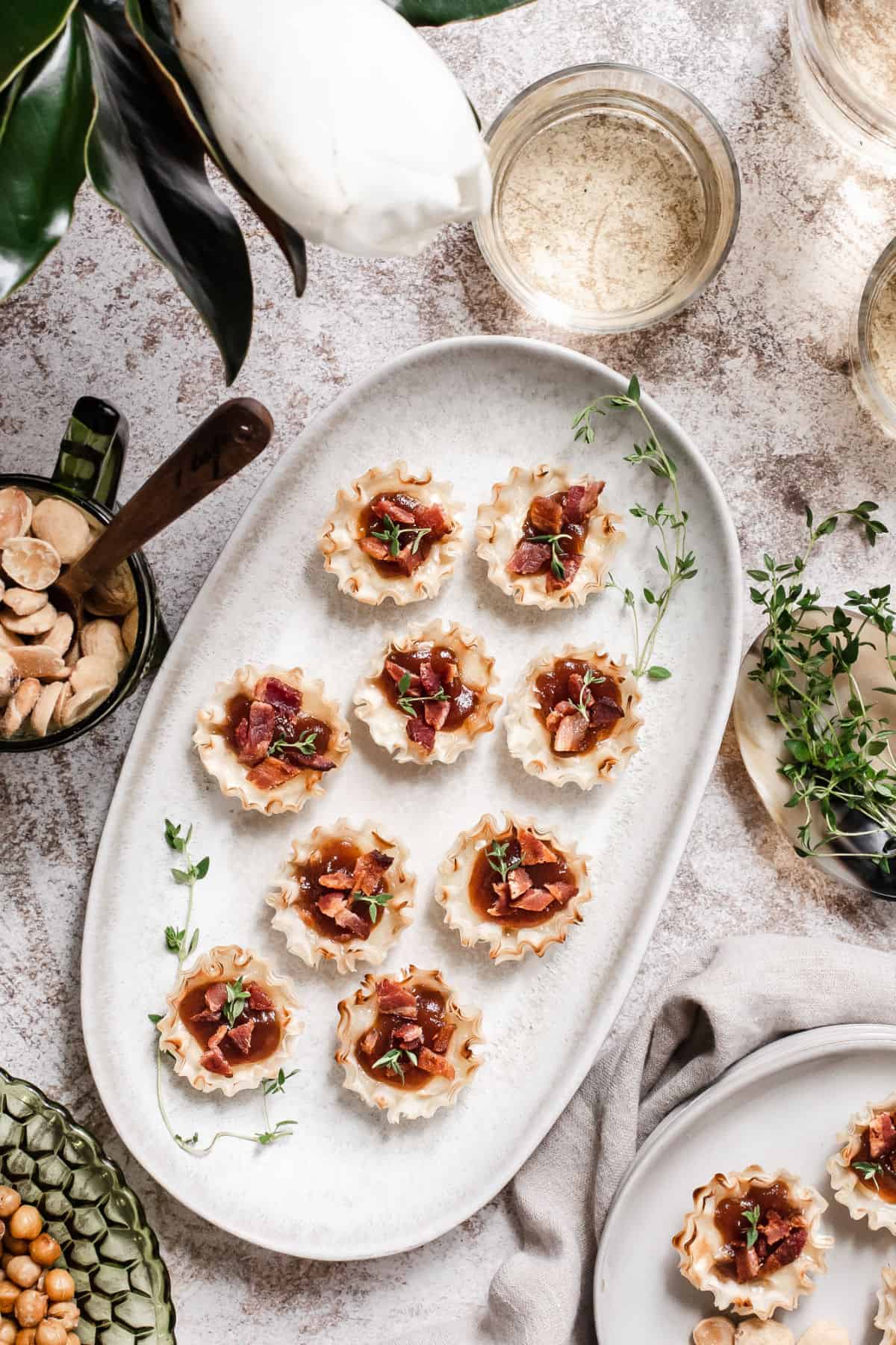 party scene with platter of phyllo cups filled with brie, apple butter and bacon overhead view