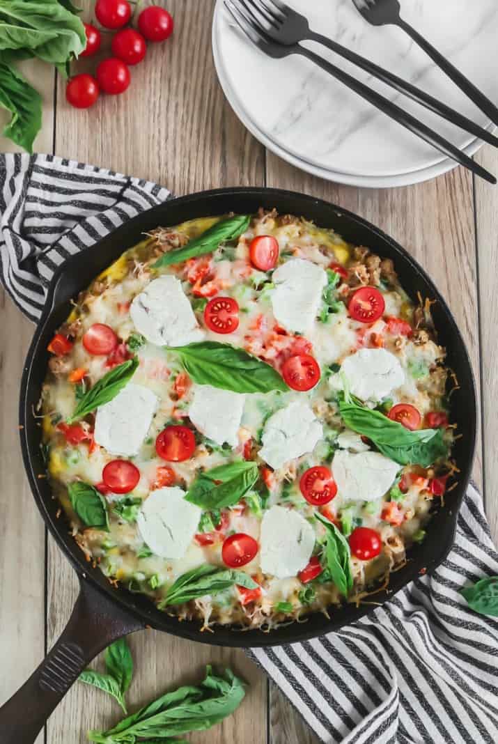 Brunch Skillet Recipe with Sausage & Hash Browns overhead view with plates and tomatoes and basil leaves