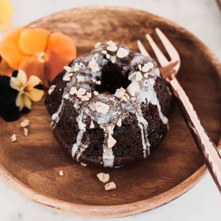 mini chocolate bundt cake recipe with icing drizzle, on wood plate.