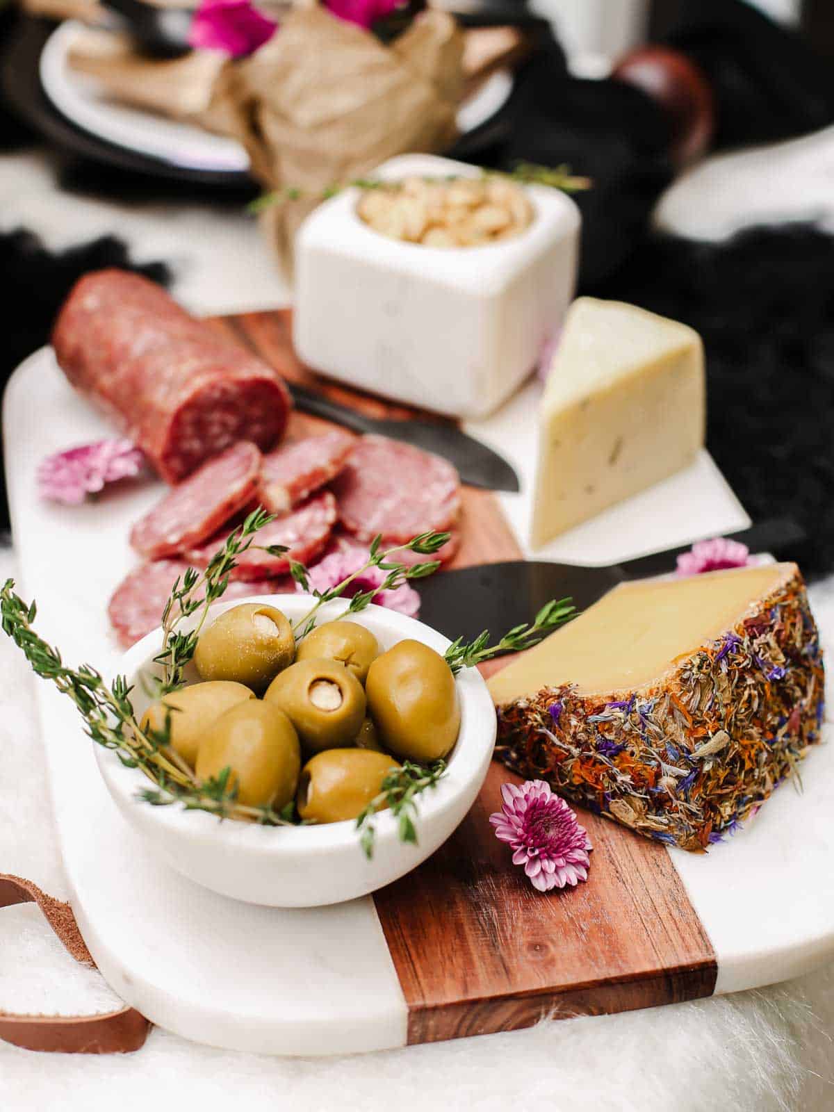 marble and wood board with cheeses and charcuterie, olives and almonds.
