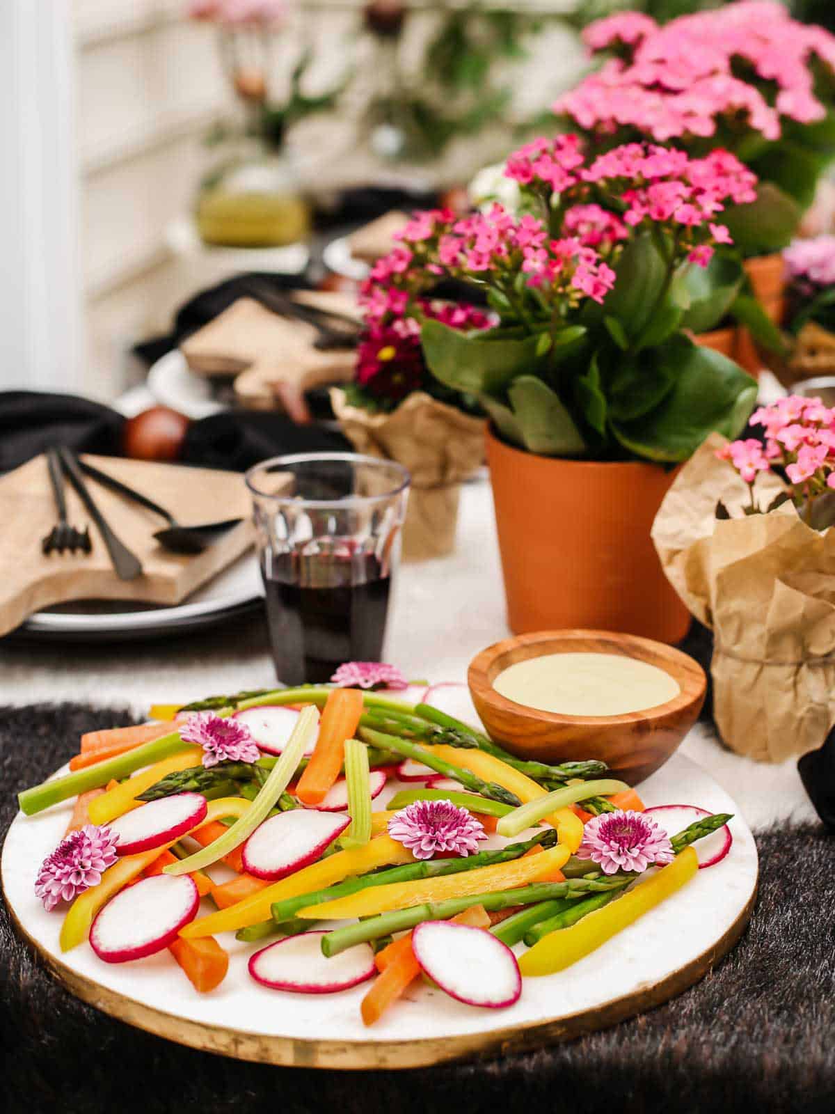 round marble board with vegetable sticks and slices, on outdoor tablescape.